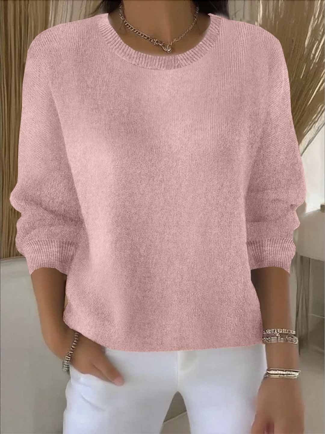 Fijngebreide oversized damestrui in roze met ronde hals, gedragen op een witte broek