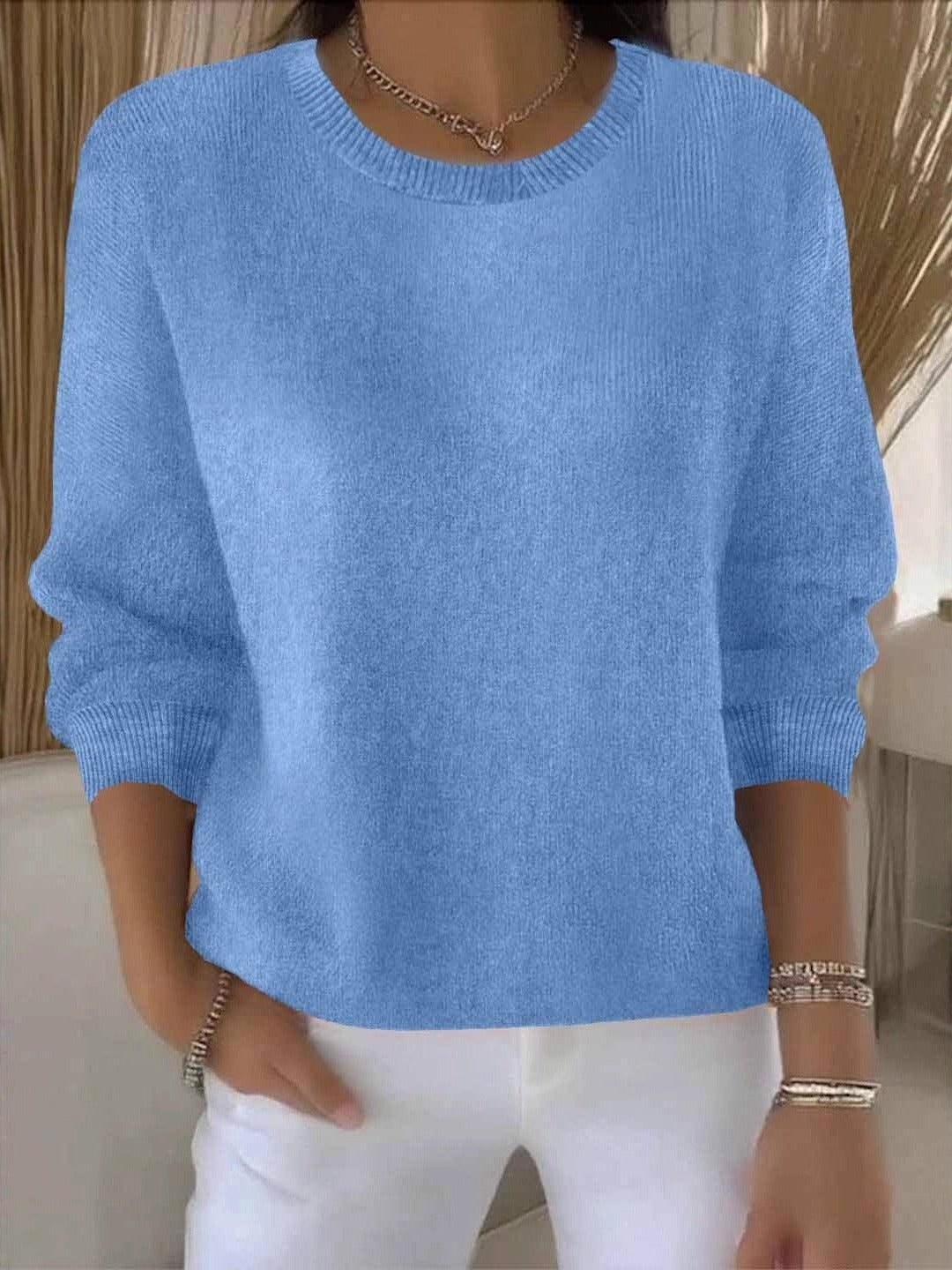 Fijngebreide oversized damestrui in lichtblauw met ronde hals, gedragen op een witte broek