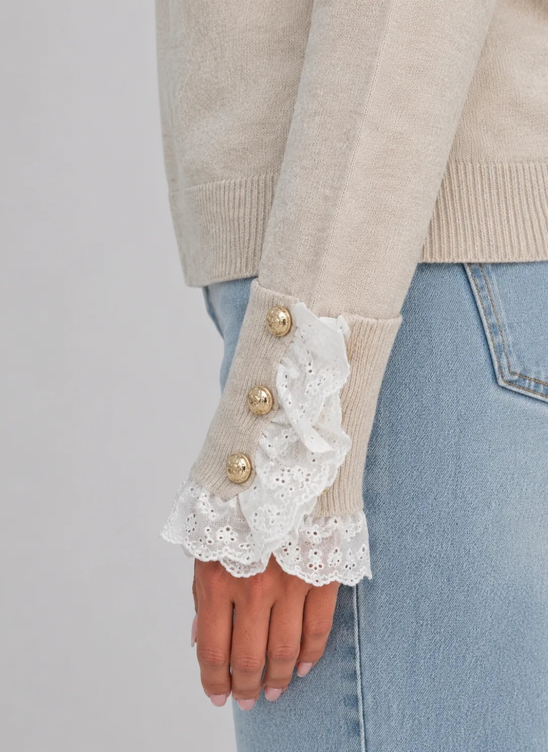 Close-up van de kanten manchet met drie goudkleurige knoopjes