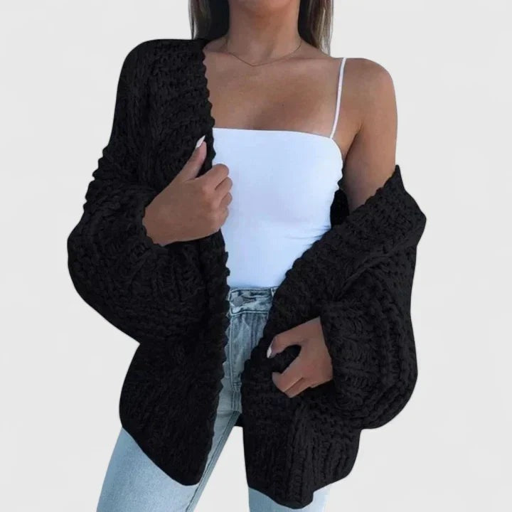 Grofgebreid oversized damesvest in zwart, open gedragen over een wit topje