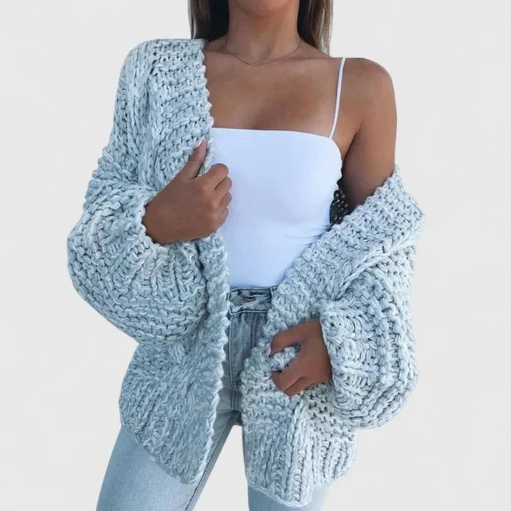 Grofgebreid oversized damesvest in lichtblauw, open gedragen over een wit topje