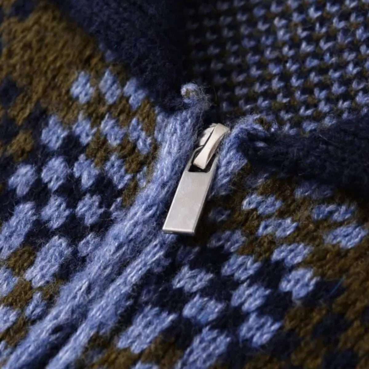 Detail van de zilverkleurige rits op het geruite breisel