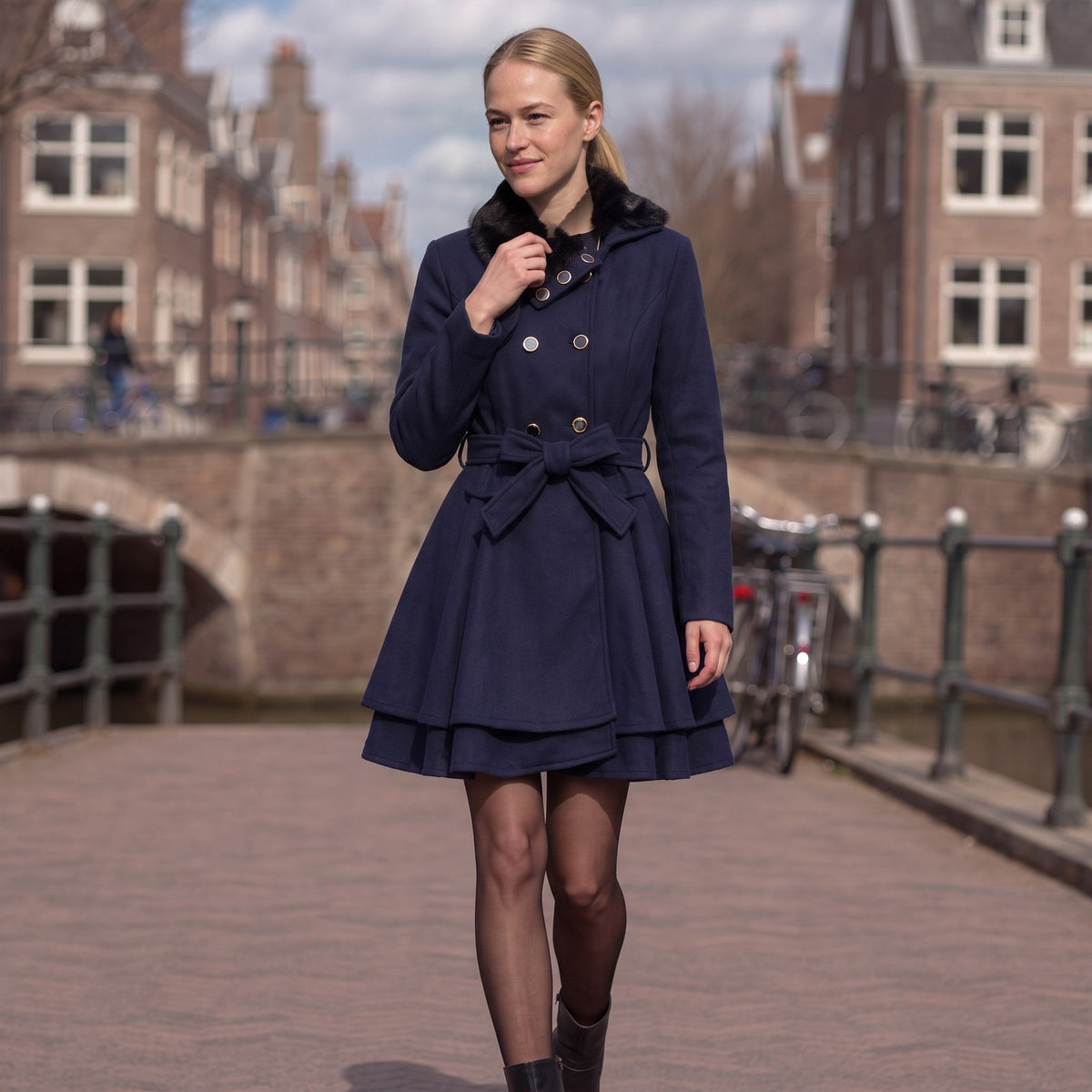Vrouw in een marineblauwe wollen jas met kunstbontkraag langs een Utrechtse gracht